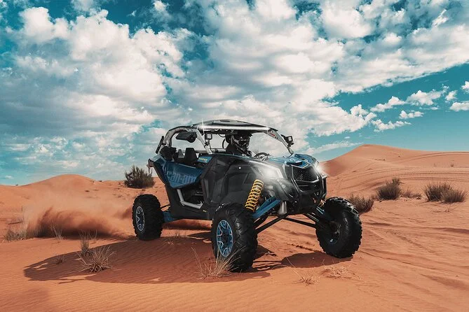 A Can-Am buggy crossing orange desert dunes